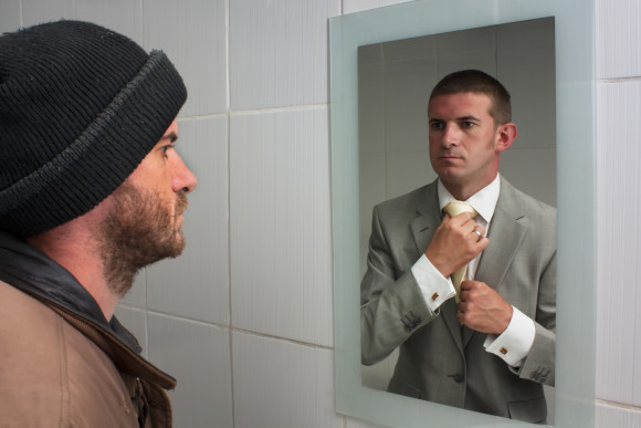 Unemployed man looking in mirror and seeing aspirations of a better future